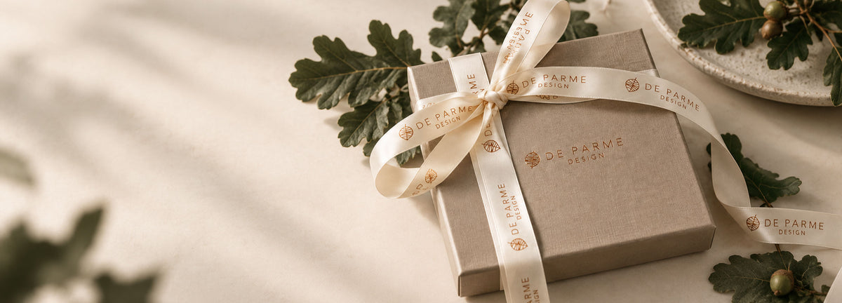 De Parme Design gift box wrapped with a signature ribbon, surrounded by oak leaves and acorns
